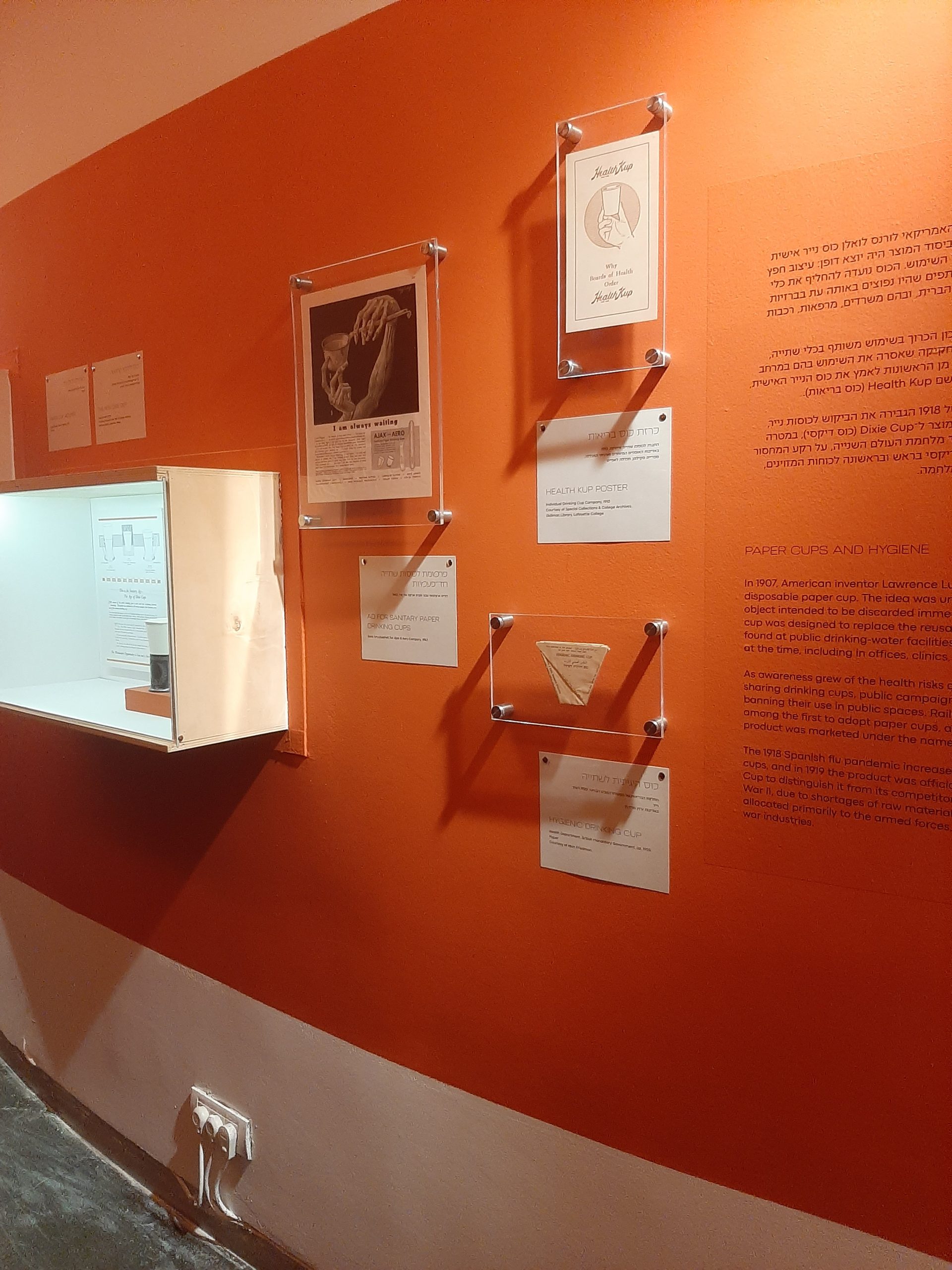 Posters from Special Collections & College Archives Dixie cup collection on display on an orange wall.